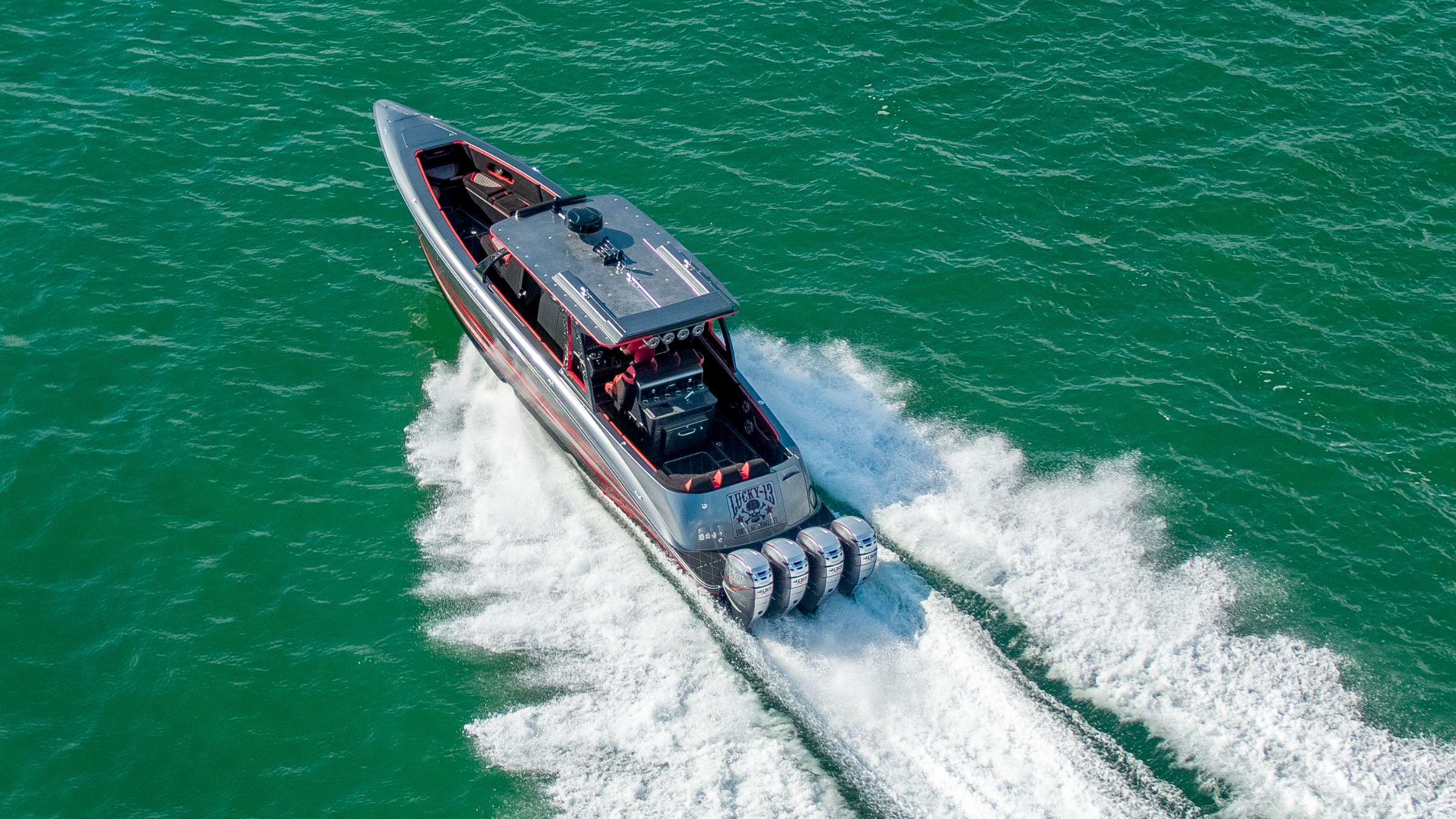 Lucky 13 at cruising speed, aerial view over open water, quad Mercury Verado outboards visible