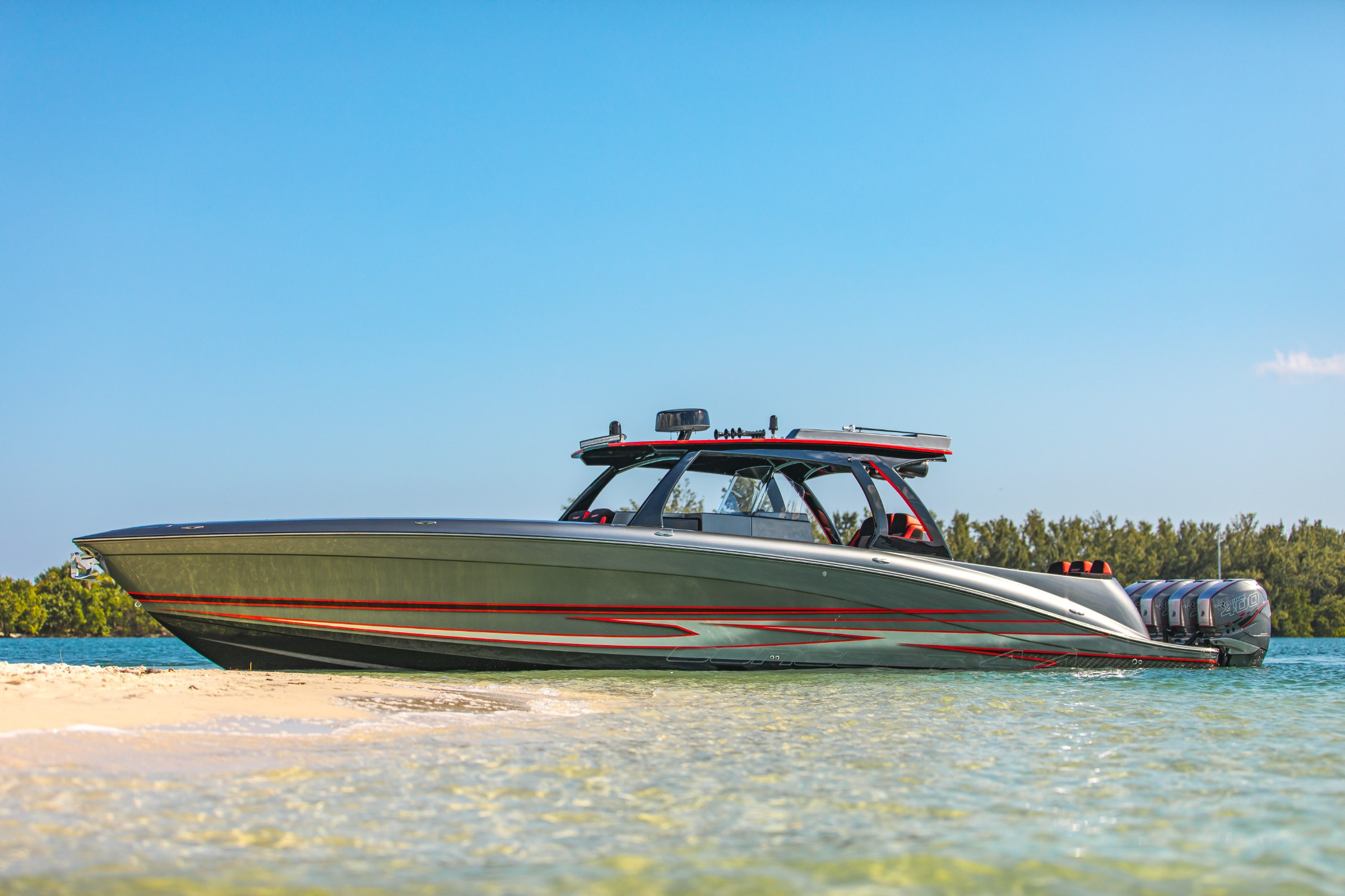 Lucky 13 custom grey hull with red accent striping, beached beneath palms