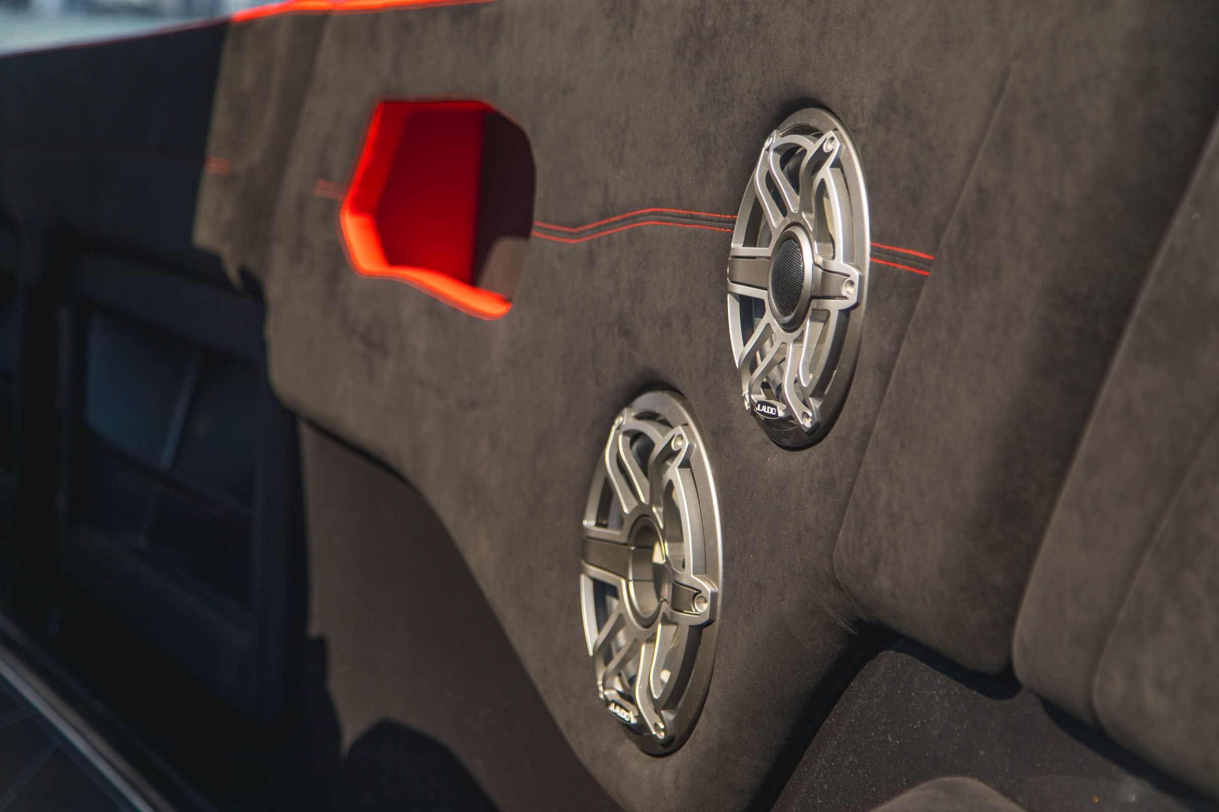 JL Audio speaker set flush into suede-trimmed panel with red stitch line